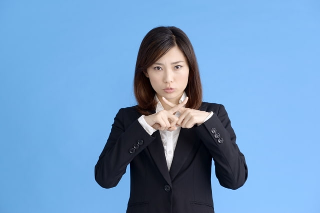 胸元でバツを作っている女性