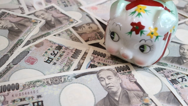 散らばっている1万円札の上にブタの貯金箱が乗っている