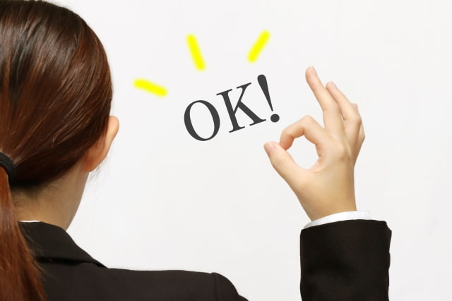 後ろ向きでOKサインをする女性