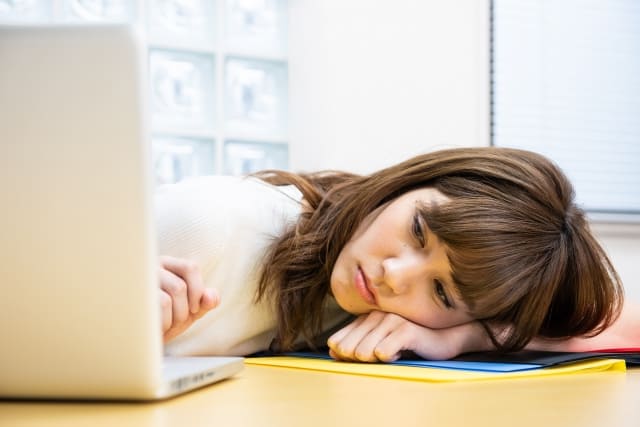 仕事を辞めたいのに言えない女性が机にうなだれている