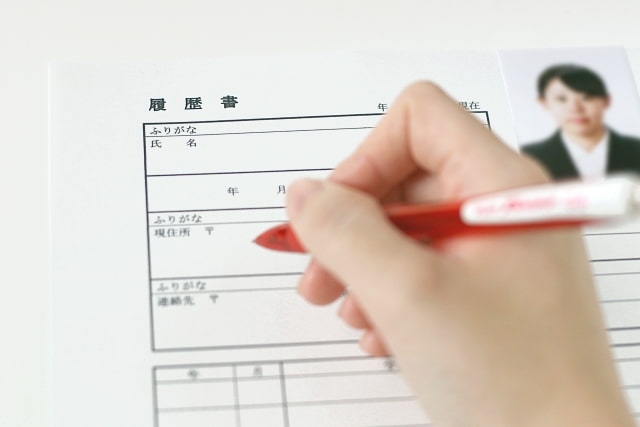 赤ペンで履歴書を記入する