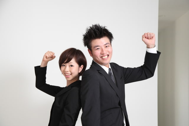 背中合わせでガッツポーズを取っている男女