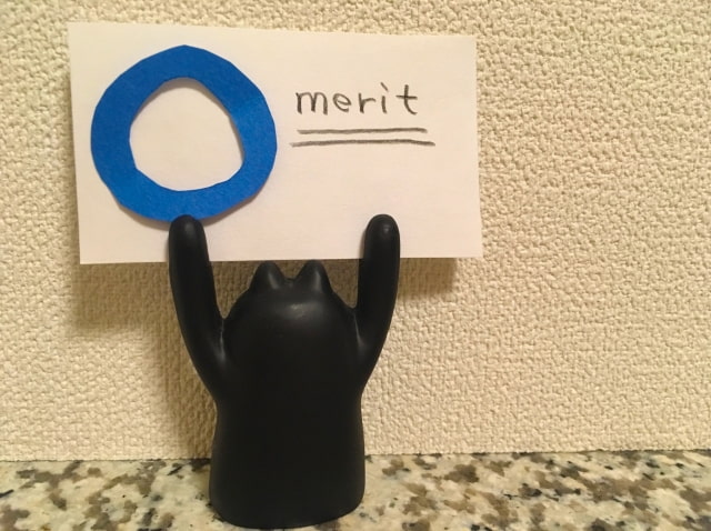 meritと書かれたメモ紙をもつ後ろ向きの黒猫