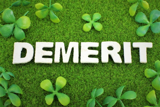 草原の上にDEMERITの文字が置かれている