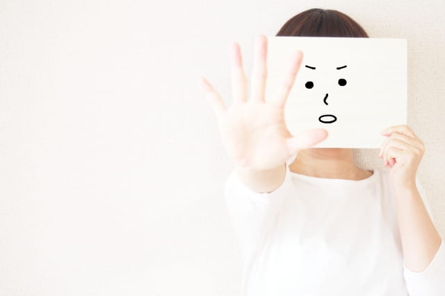 人と関わらない仕事のデメリットを紙に書いた顔で顔を隠して話す女性