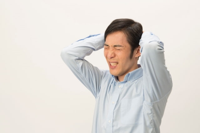 両手で頭を抱えて嘆く男性